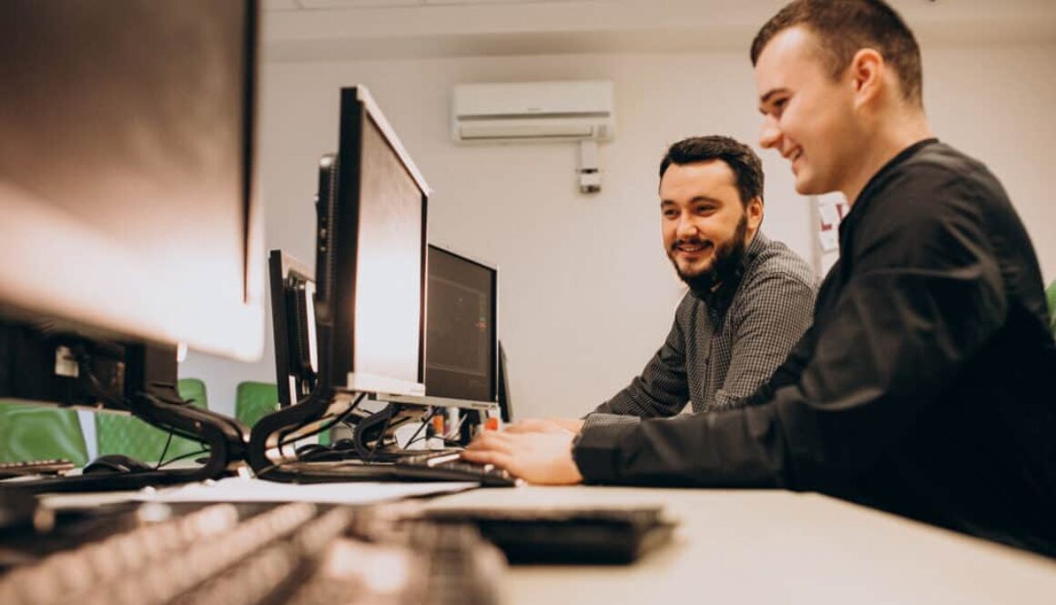 Two yound male IT support workers at a desk