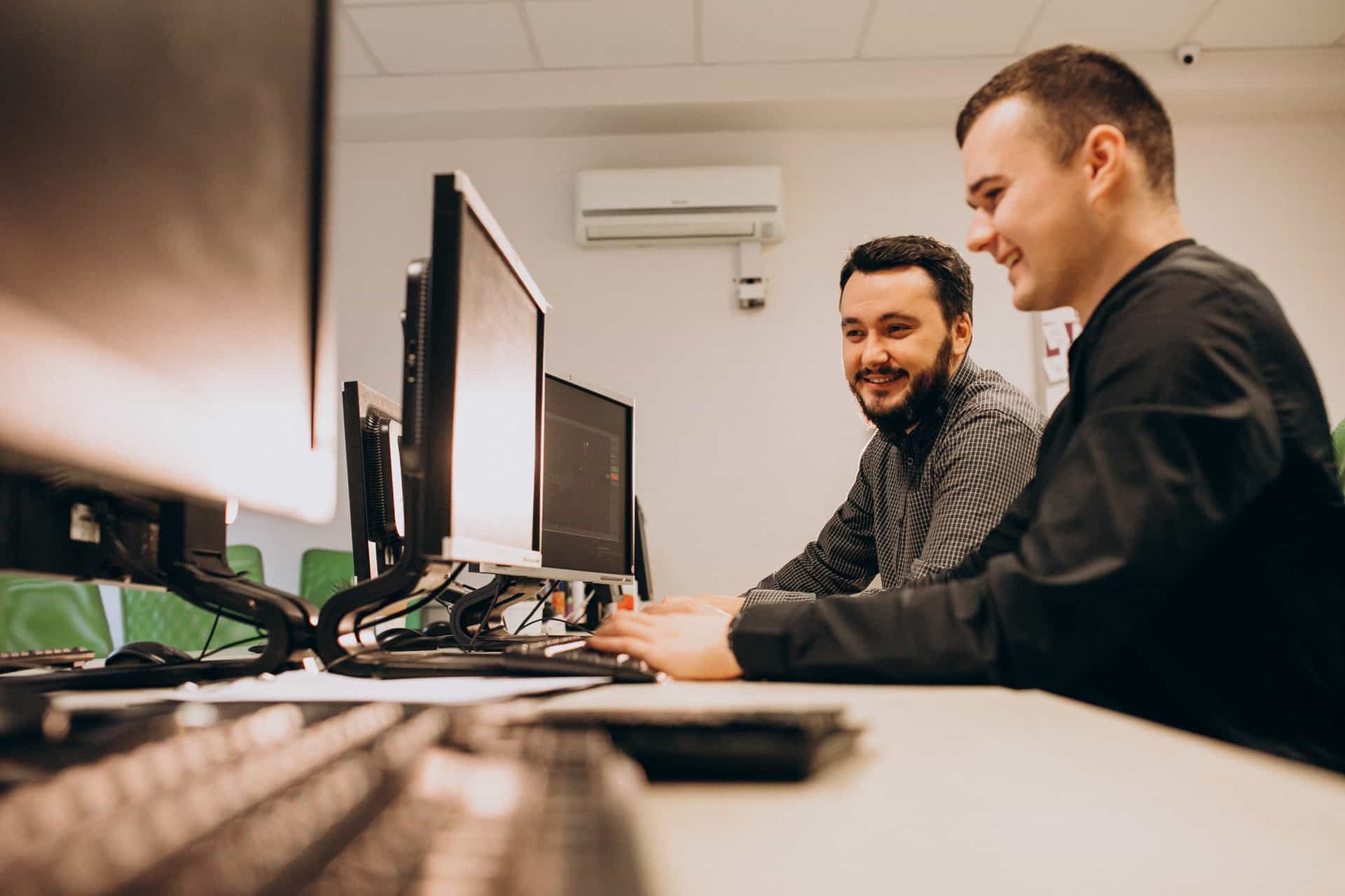 Two yound male IT support workers at a desk