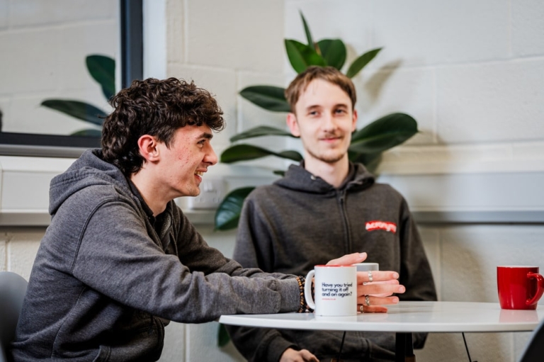 two people sat around a table drinking a cup of tea