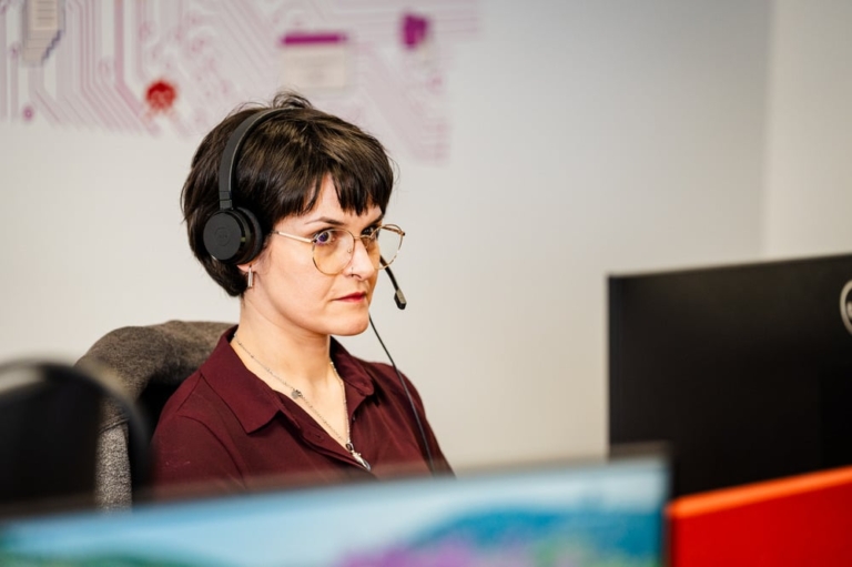 a woman sat at her desk wearing a headset