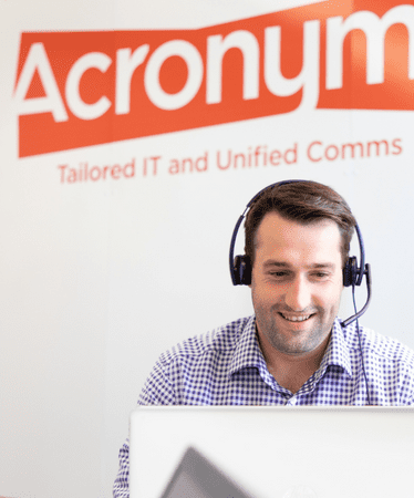 An acronyms employee taking a call on his computer