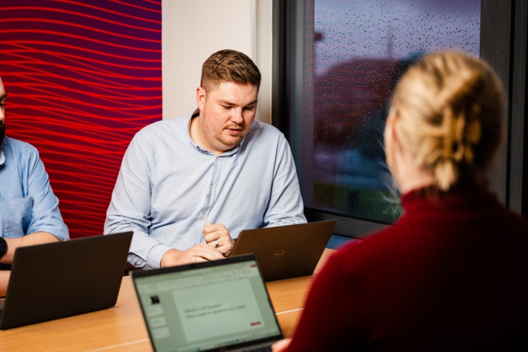 Three People Sat Around A Table Discussing Healthcare Clients